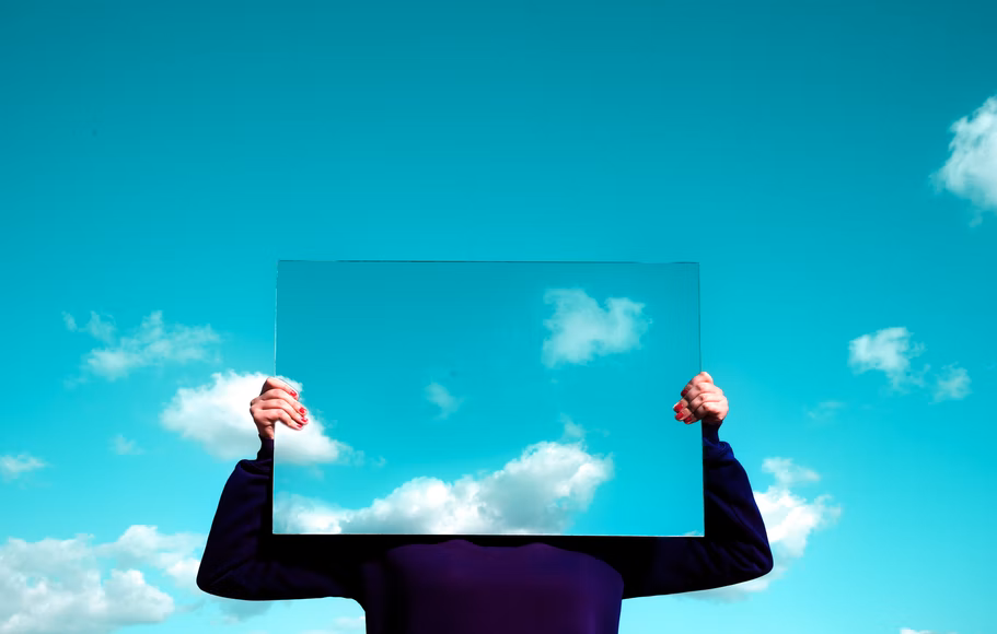 man in black suit raising mirror in hands